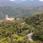 Imatge distant del conjunt de Santa Pellaia, format per l'església, la rectoria i dos masos; enmig de la immensitat de les Gavarres. De l'església en destaca la torre campanar de planta quadrada coronat amb cúpula.