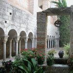 A l'entrada de Girona a les Gavarres trobem un dels monestirs benedictincs més antics de Catalunya. La imatge ens mostra el claustre del cenobi, amb la seva doble arcuació de columnes amb els capitells amb motius vegetals. En el primer terme hi ha el pou d'aigua amb la politja i un càntir.