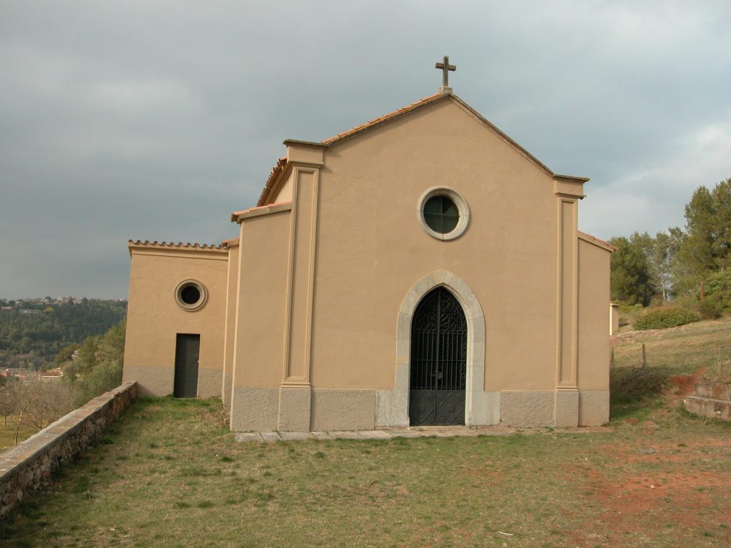 La imatge mostra la capella del Calvari, final del via crucis que puja per la muntanya. A l'edifici pintat amb tons rosats en destaca l'entrada en forma d'arc apuntat i el rosetó superior. Al mig de la teulada hi ha una creu.