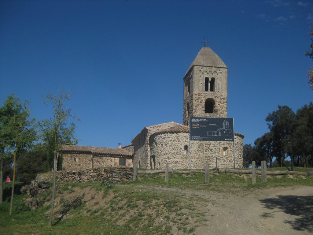 La imatge és una vista completa de l'església i la rectoria de Fitor feta a certa distància. Darrera seu la vista ens porta fins al Massís del Montgrí. Santa Coloma és d'estil romànic, com ho denota el seu campanar de base quadrangular i el tercer pis de finestres geminades i arquacions llombardes. L'entrada a l'església es fa per un lateral amb una porta adovellada d'arc de mig punt. L'església ha estat restaurada i la rectoria és un equipament municipal, la qual cosa ofereix a l'indret moltes possibilitats d'ús públic. El seu aplec, cada tercer diumenge d'octubre és una de les cites importants pels gavarrencs.