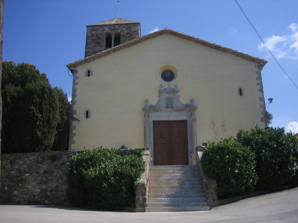 Imatge frontal de l'església parroquial de santa Margarida de Quart. Darrera unes escalinates d'accés veiem la imponent façana pintada de groc amb la porta d'entrada emmarcada per un relleu neoclàssic. Al darrea en despunta el campanar romànic de planta quadrada i dos pisos de finestres geminades.
